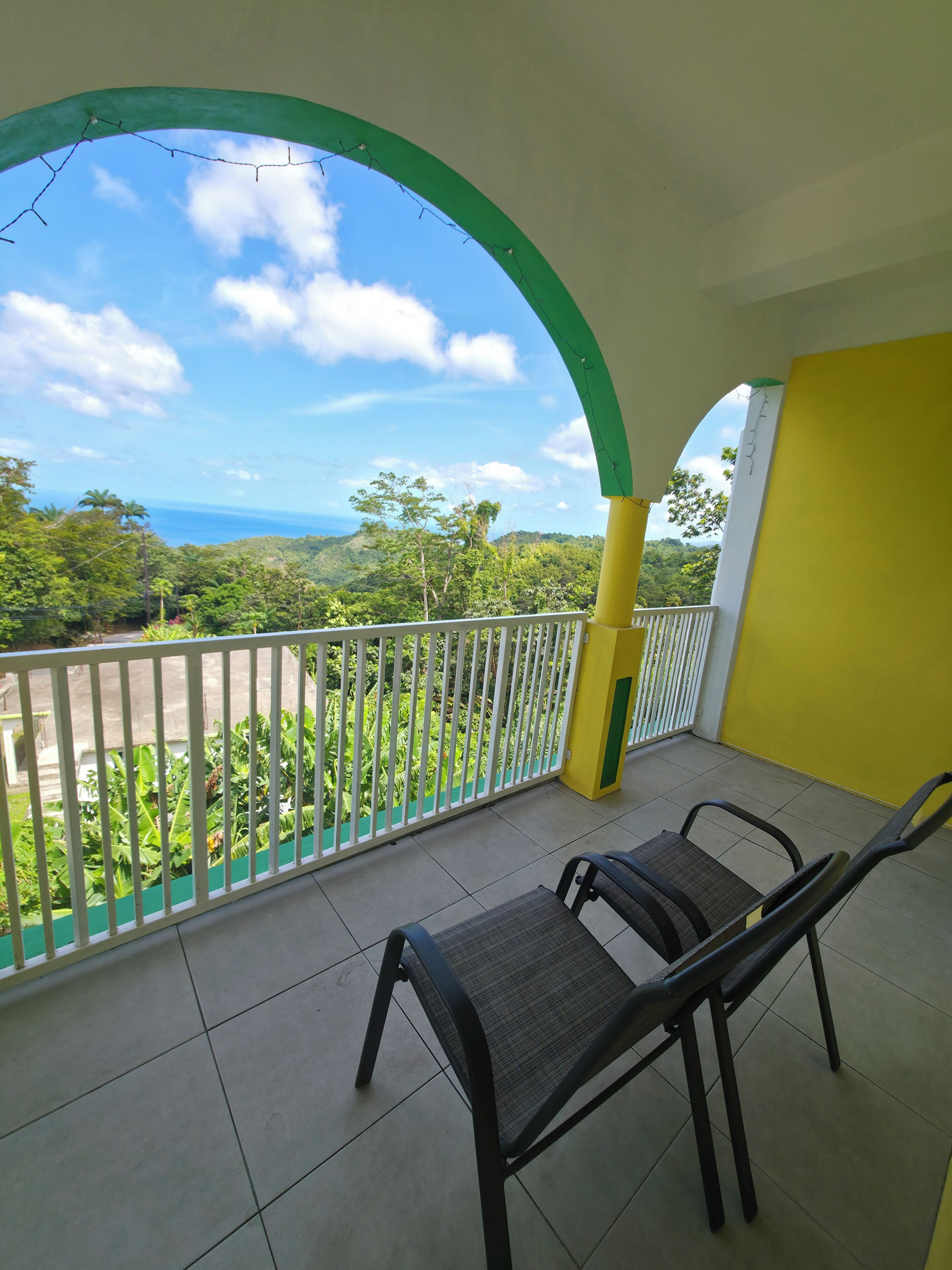 Ein Balkon mit Blick auf eine üppige Landschaft und das Meer.