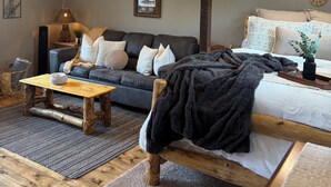 A cozy room with a wooden ceiling, a sofa, a bed, and a small table. - The Perch Point Studio- Peaceful getaway in Florrisant (Florissant)