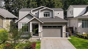 A two-story house with a garage, a front porch, and a driveway. - Luxury 4BR | Steps to Beach, Hot Tub & Theatre (Surrey)