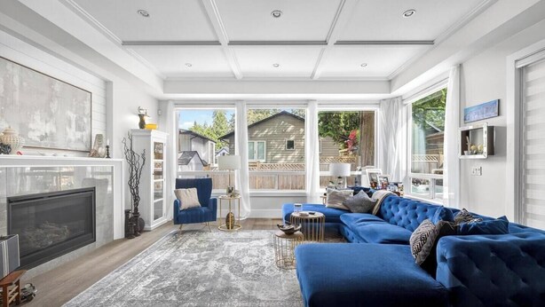 A spacious living room with a large sectional sofa, a fireplace, and a view of the backyard. - Luxury 4BR | Steps to Beach, Hot Tub & Theatre (Surrey)