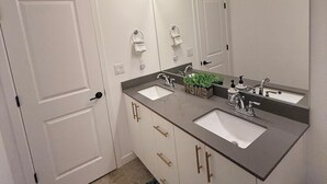 A bathroom with two sinks, a large mirror, and wall-mounted lights.