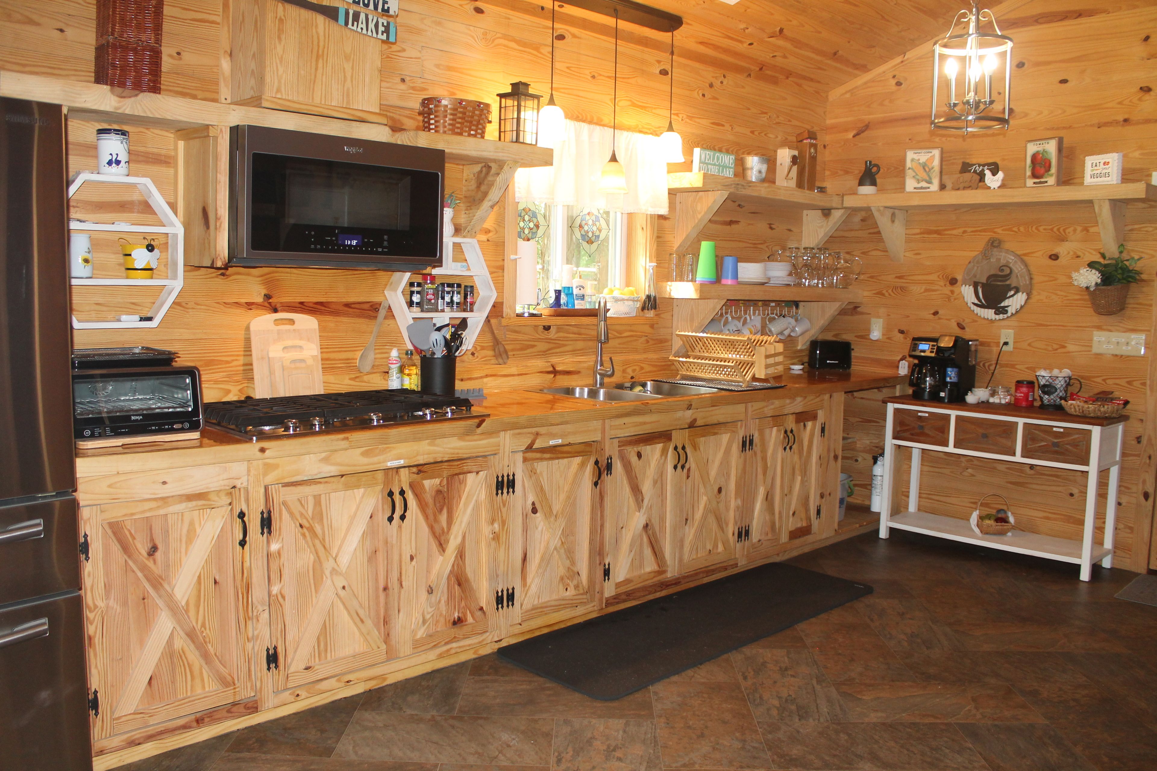 A kitchen with wooden cabinets, a microwave, a stove, and various kitchen items.