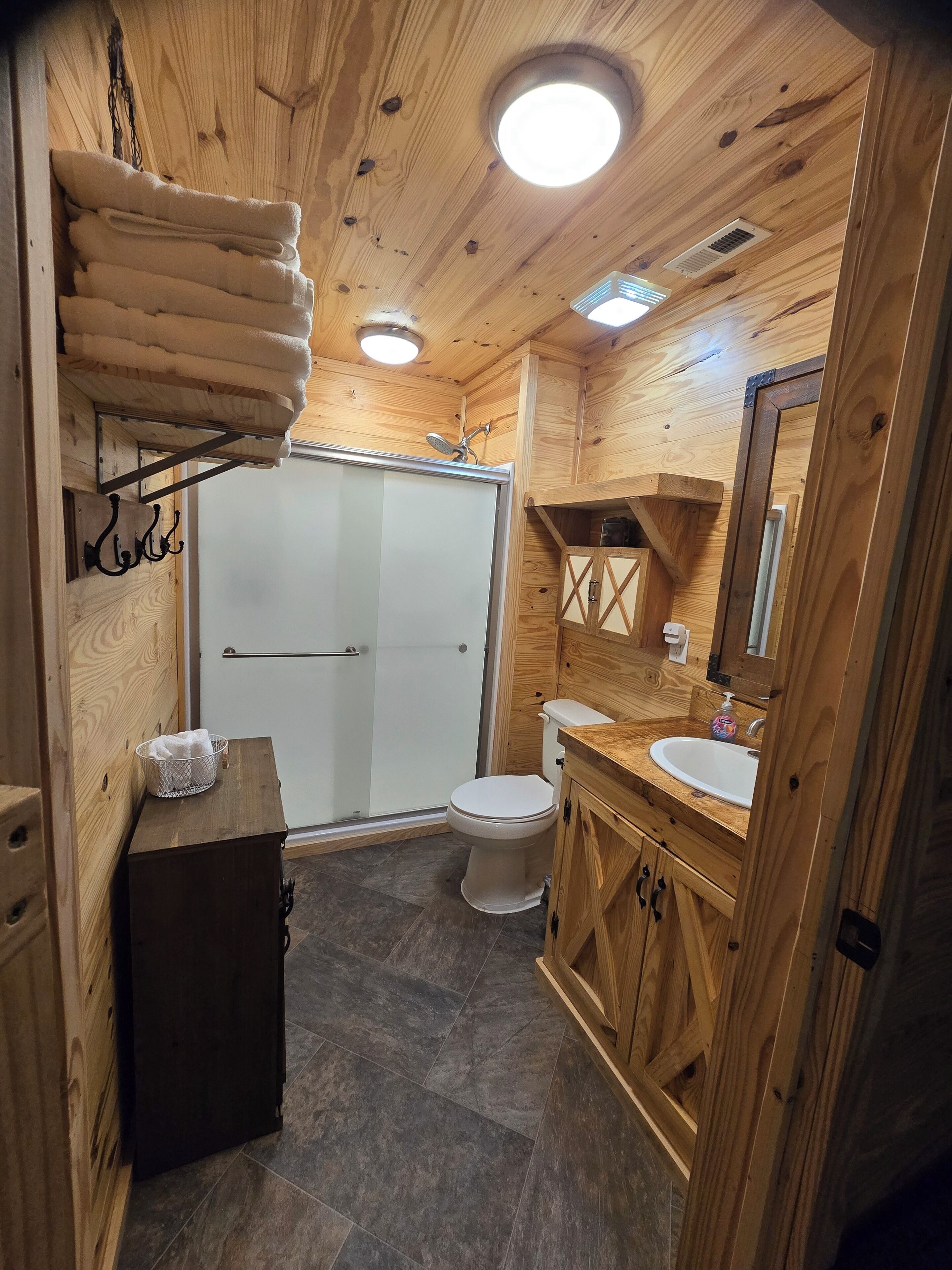 Et interiør i træ med toilet, vask og brusebad.