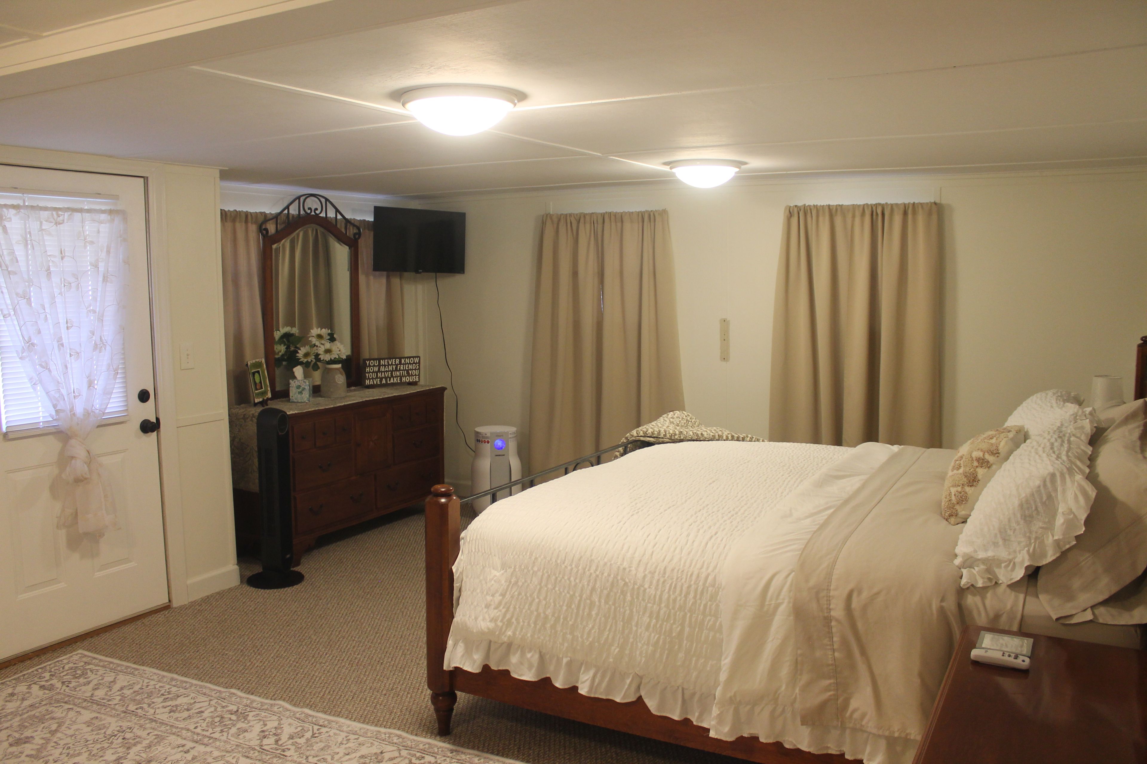 A bedroom with a bed, dresser, and a television on the wall.