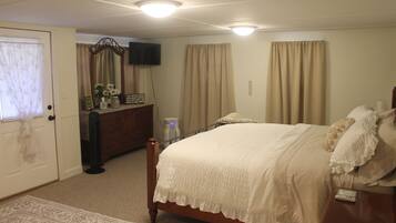 A bedroom with a bed, dresser, and a television on the wall.