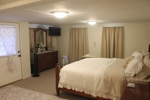 A bedroom with a bed, dresser, and a television on the wall.