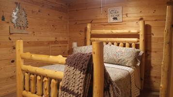 A wooden cabin interior with a bed, a wall sign, and a decorative tree cutout.