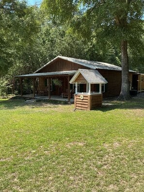 A wooden cabin with a porch and a covered outdoor seating area.