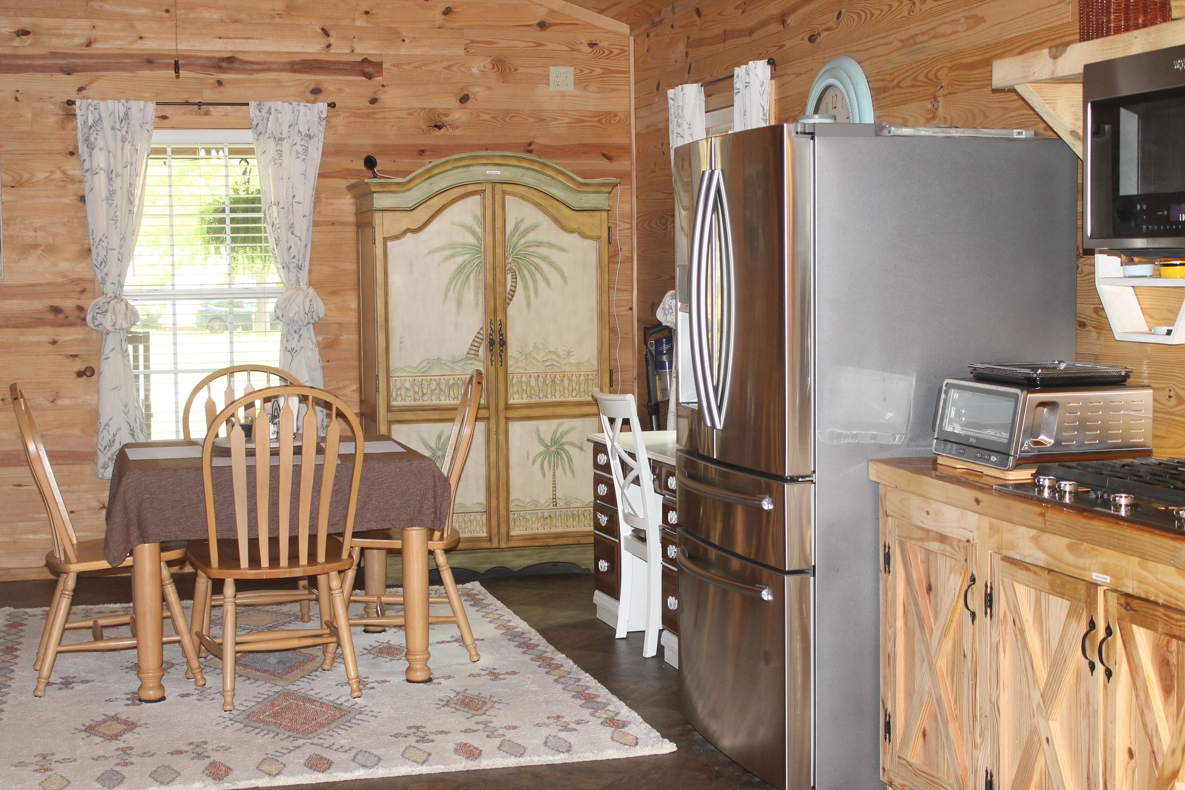 Un intérieur en bois comprenant une table à manger, des chaises, un réfrigérateur, un four à micro-ondes et une cuisinière.