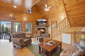 A wooden cabin interior with a fireplace, a dining area, and a staircase. - Lazy Bear Retreat - Idilic Mountain Getaway (Blue Ridge)