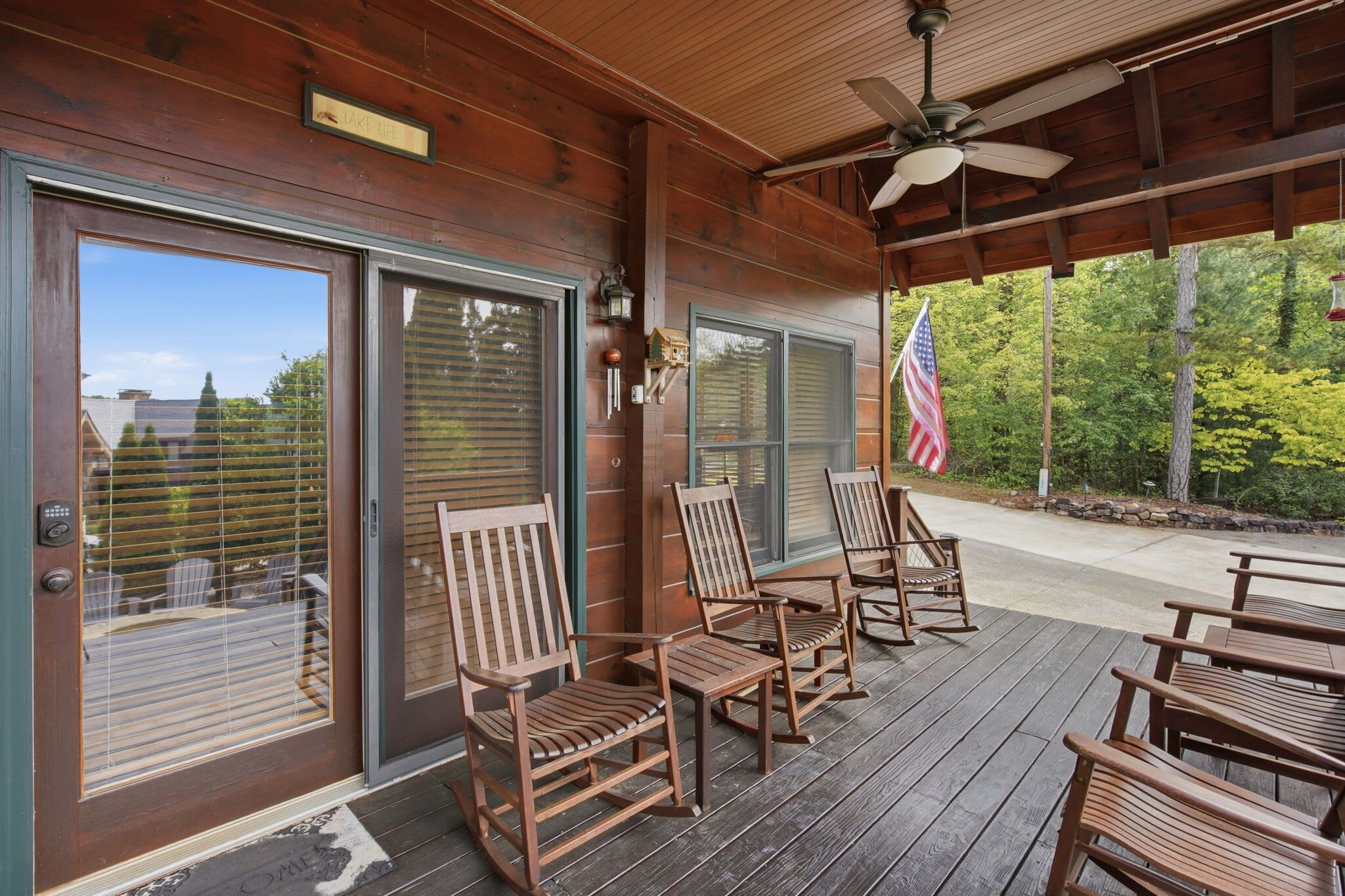A covered porch with wooden chairs and a flag.