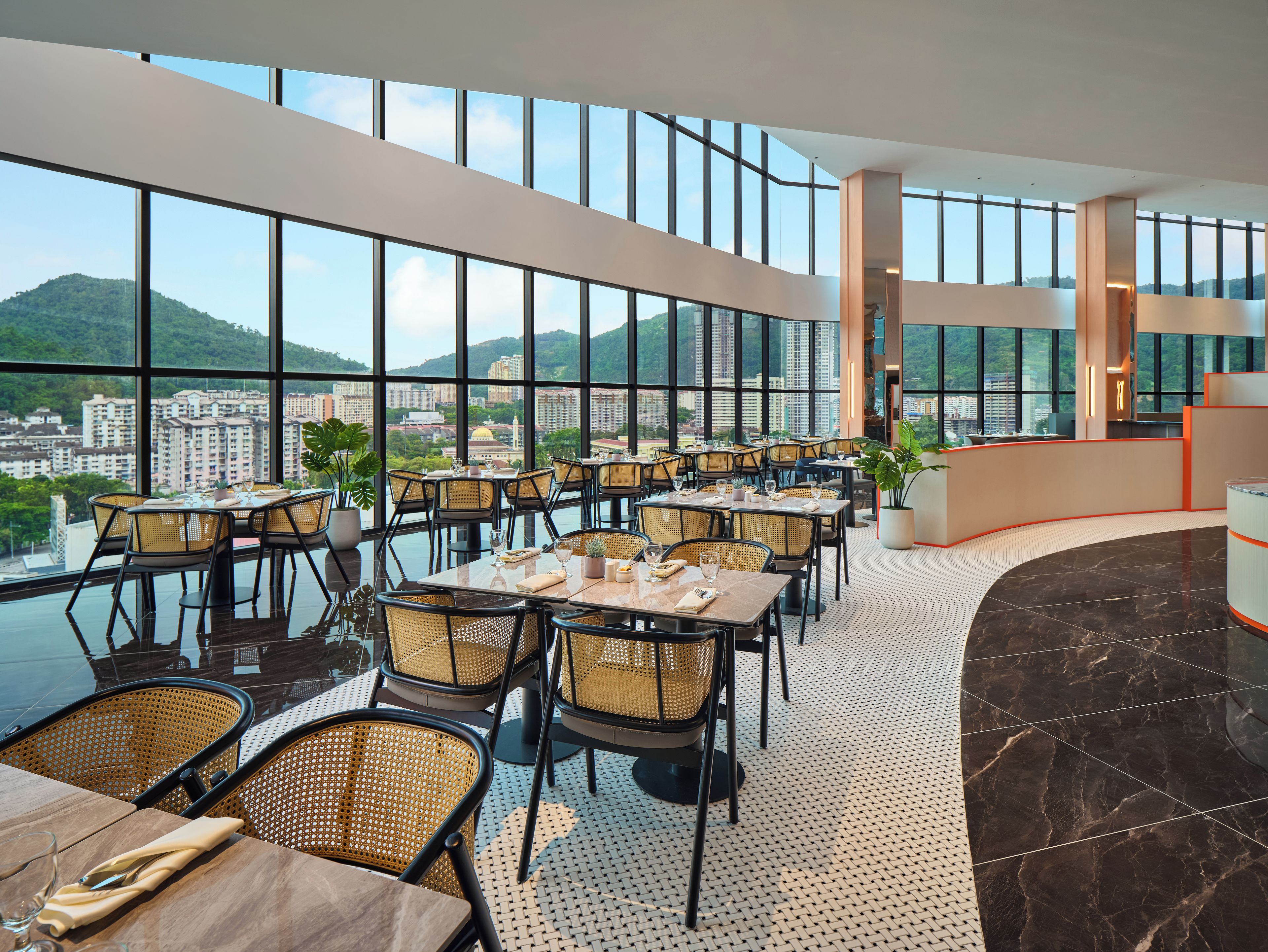 A modern restaurant with high ceilings, large windows, and a view of a cityscape.