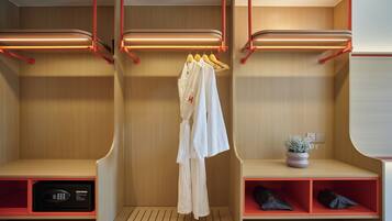 Une chambre d’hôtel avec une armoire en bois, un peignoir suspendu, une petite plante et un coffre-fort.