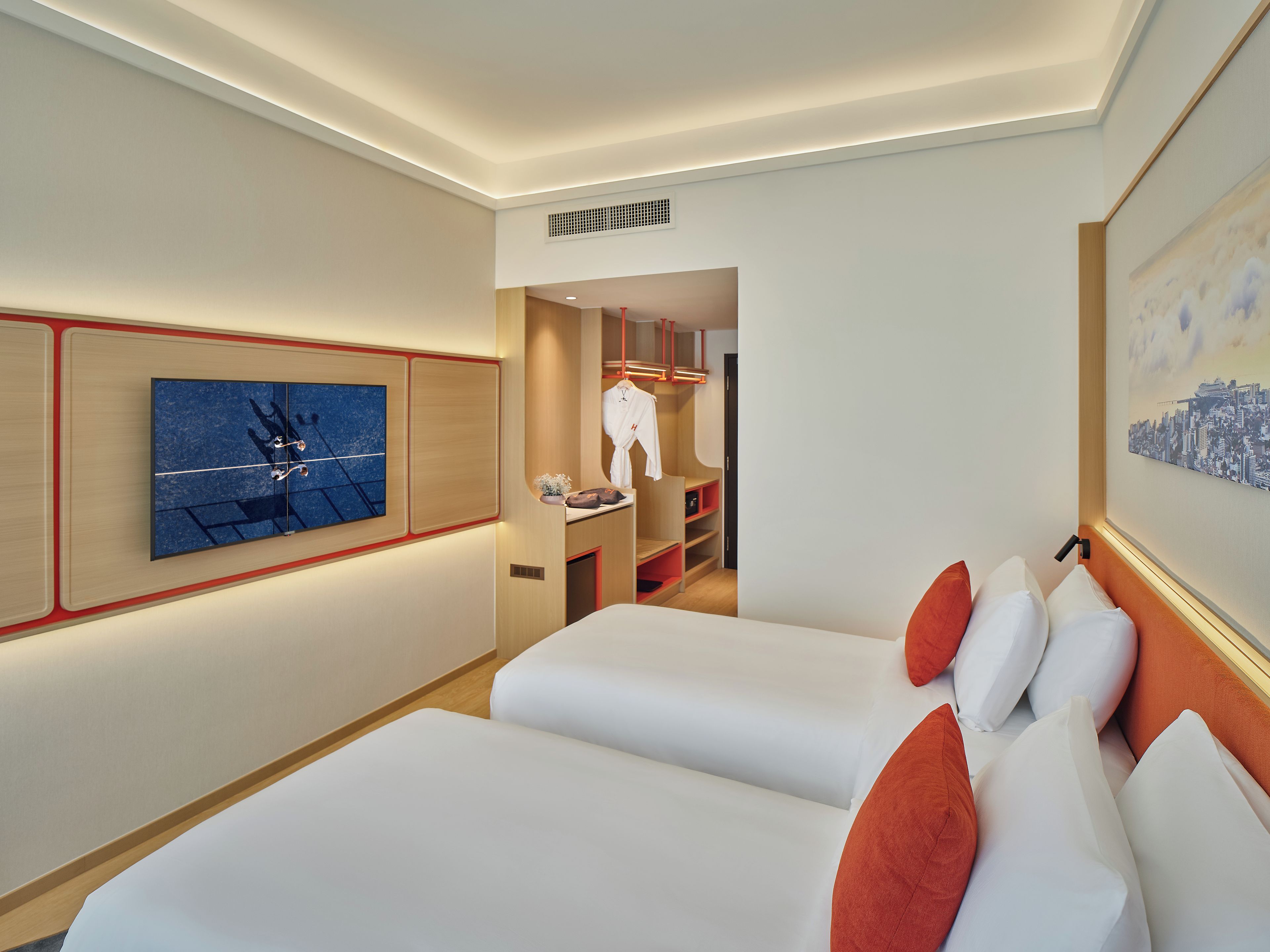 A hotel room with two beds, a painting on the wall, and a cityscape artwork.
