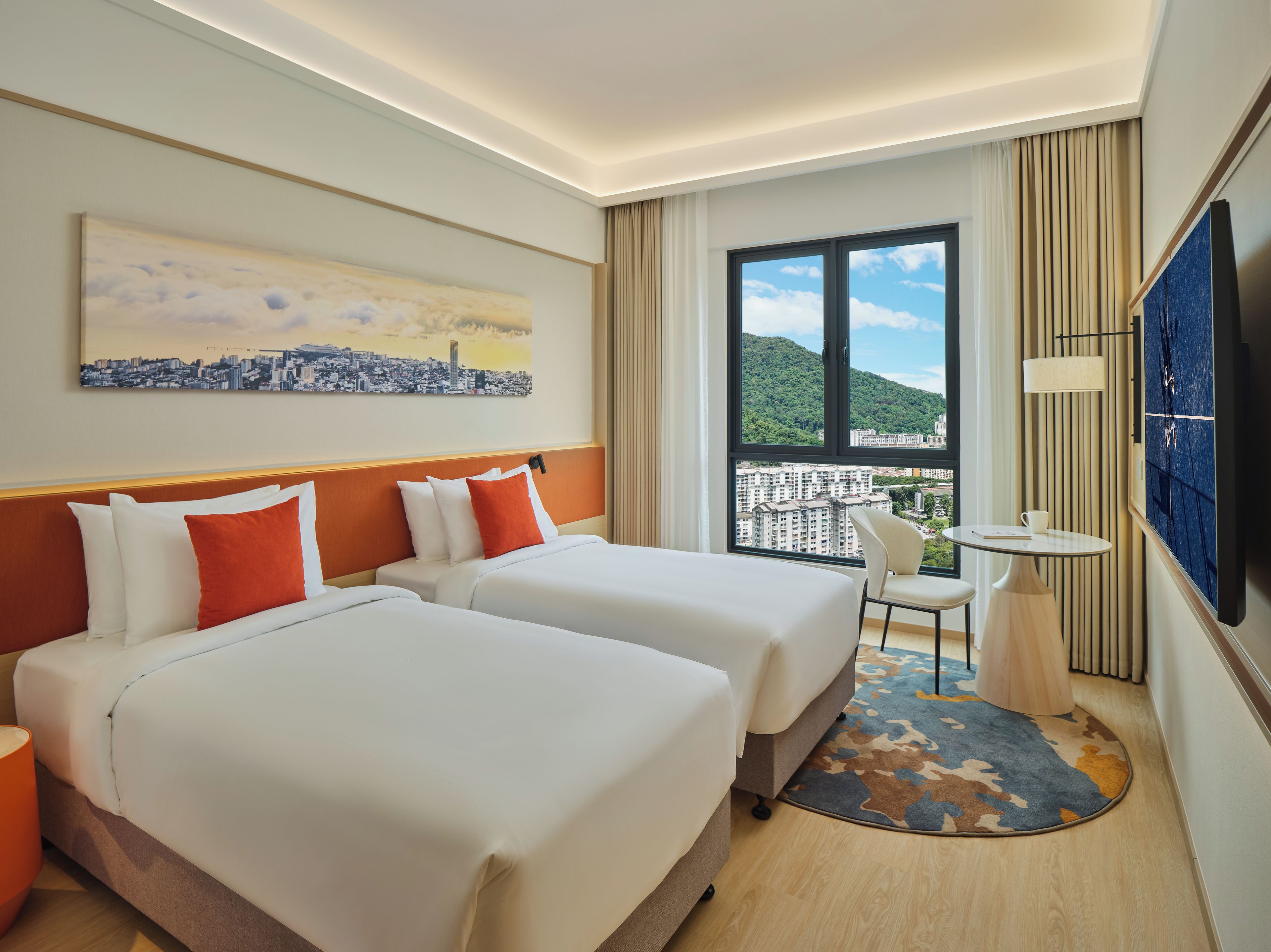 Habitación de hotel con dos camas, un cuadro de un paisaje urbano, un ventanal con vistas, una mesita y un televisor.