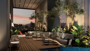 A modern outdoor lounge area with seating, a pool, and a view of the sunset. - Oakwood Slipi Jakarta (Jakarta)