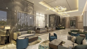 En moderne lobby med marmorvægge, en receptionsdisk, sofaer og en lysekrone.
