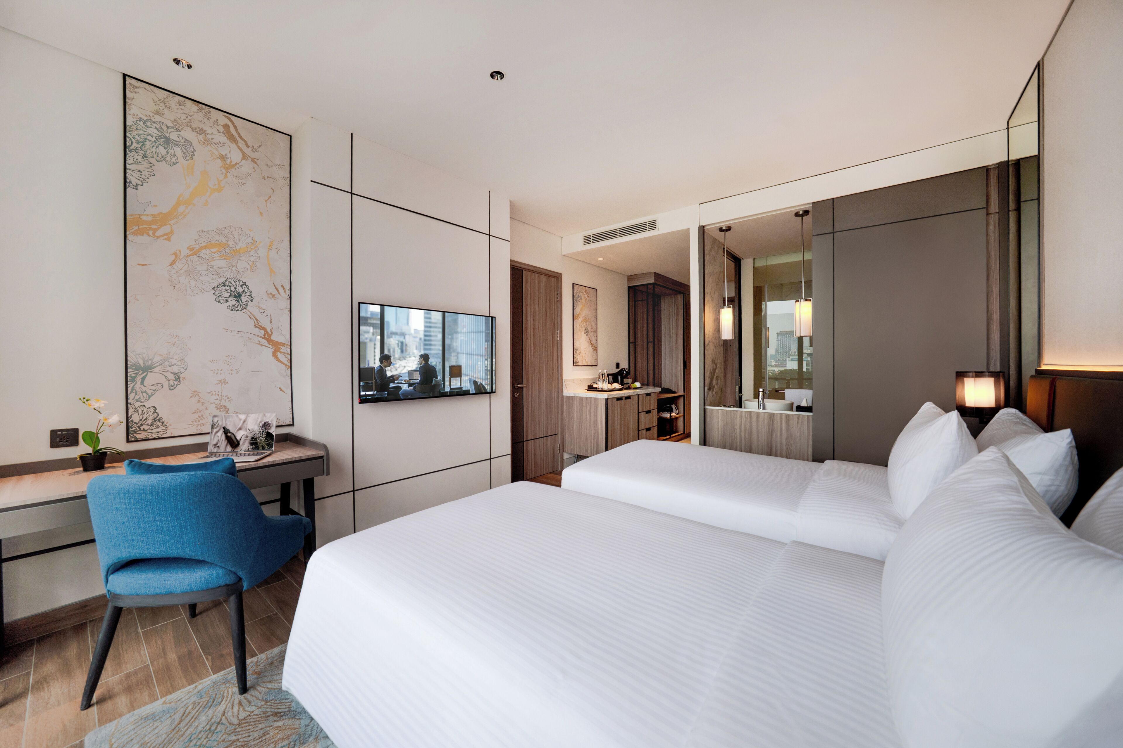 Habitació d'hotel moderna amb un llit gran, un escriptori, una cadira, un mirall ampli i vista a la ciutat.