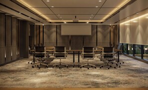 A conference room with a large table, six chairs, a projector screen, and a carpeted floor. - Oakwood Slipi Jakarta (Jakarta)