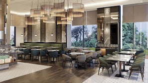 Un intérieur de restaurant moderne, avec de hauts plafonds, des luminaires suspendus et une vue sur la verdure à l’extérieur.