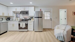 Une cuisine moderne avec des meubles blancs, des appareils en acier inoxydable et un plancher en bois.