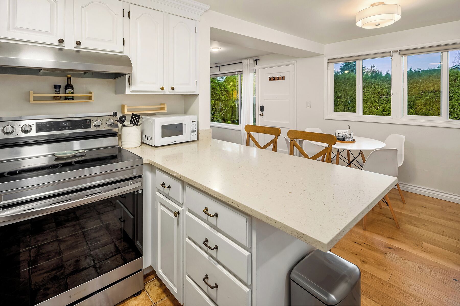A modern kitchen with white cabinetry, stainless steel appliances, and a breakfast bar.