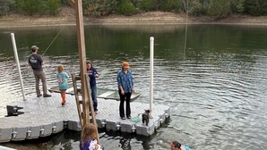 A dock extending into a calm lake with people standing on it. - A little bit of heaven on a fun filled ranch outside quaint Brenham (Brenham)