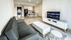 Ein modernes Wohnzimmer mit einem grauen Sofa, einem weißen Couchtisch und einem Fernseher auf einem weißen Lowboard.
