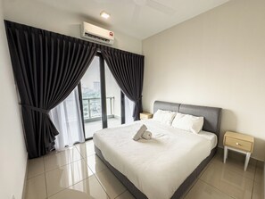 Quarto de hotel com uma cama, mesa de cabeceira, ar condicionado e vista panorâmica da cidade pelas amplas janelas.