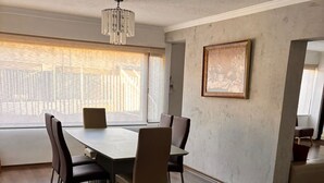 A dining area with a table and chairs, a chandelier, a painting on the wall, and a window with blinds. - Apartment near Carolina Park (Quito)