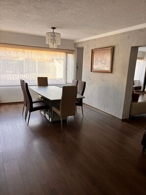 A dining area with a table and chairs, a chandelier, a painting on the wall, and a window with blinds. - Apartment near Carolina Park (Quito)