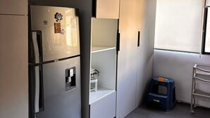 A modern kitchen with built-in appliances, a small stool, and a window with blinds. - Apartment near Carolina Park (Quito)