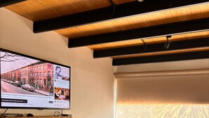 A room with a wooden ceiling, a TV on a stand, a window with a view, and a chair. - Apartment near Carolina Park (Quito)