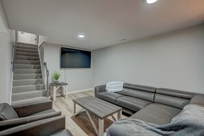 Un salon moderne avec un canapé, une table basse, un téléviseur et un escalier.