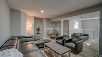 A modern living room with a sectional sofa, a coffee table, and a dining area with a table and chairs.