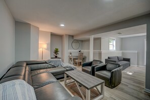 Una sala de estar moderna con un sofá modular, una mesa de centro y una zona de comedor con mesa y sillas.