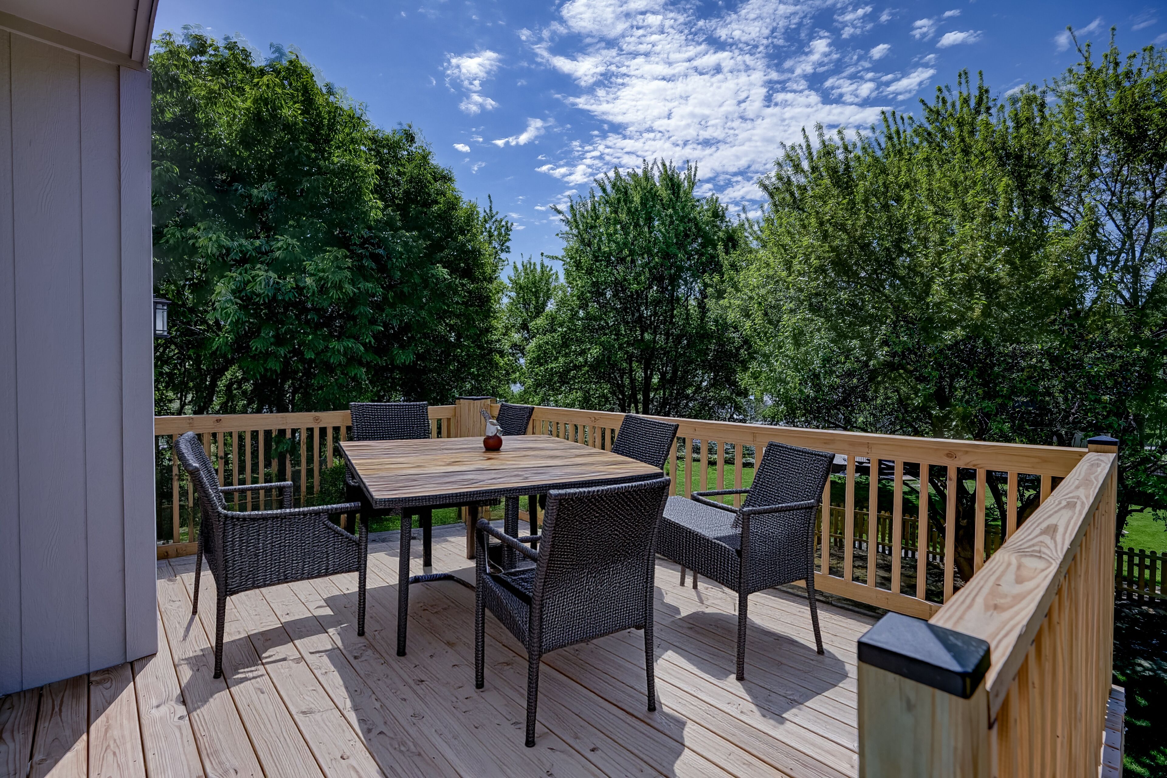 Eine Holzterrasse mit Tisch und Stühlen, umgeben von einem Hollerker.