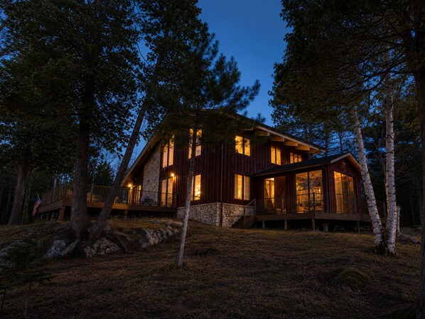 A cabin with a stone facade, large windows, and a deck. - Private Architectural Waterfront Lodge on Eagles Nest #2 (Ely)
