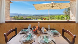 Mesa para dos con vista a un viñedo y montañas a través de una ventana.