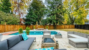 A backyard with a swimming pool, outdoor furniture, and a wooden fence.