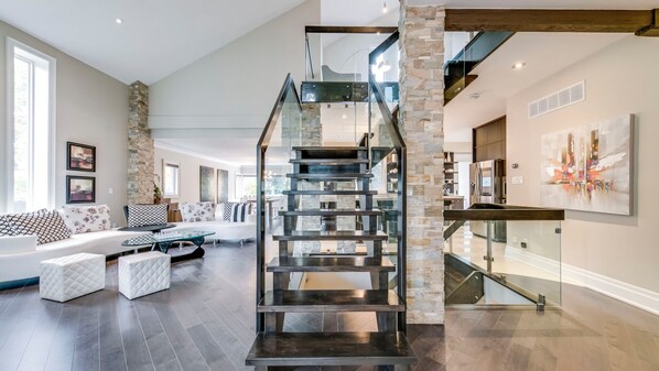 A modern interior with a central spiral staircase, a living area with a sofa and ottoman, and a dining area with a glass table.