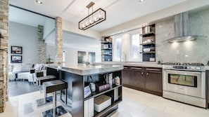 Una cocina moderna con una isla central, electrodomésticos de acero inoxidable y una pared decorativa de piedra.