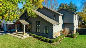 A modern two-story house with a stone foundation, a garage, and a well-maintained lawn.