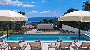 A pool with lounge chairs and umbrellas, a view of the sea, and a building with a red roof. - Villa Maria - Heated Pool, Sea & Mountain Views, Basketball & Badminton Court (Gata)
