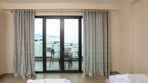 Una camera d'albergo con un balcone, un letto con un asciugamano arrotolato e un tavolo con sedie.
