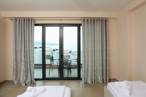 Ein Hotelzimmer mit Balkon, einem Bett mit gerolltem Handtuch und einem Tisch mit Stühlen.