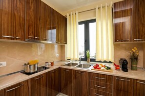 A modern kitchen with wooden cabinets, a double sink, and a window with curtains. - Velaris Sea View Balcony 108, Vlore, Albania (Vlore)