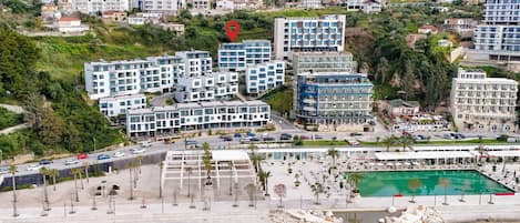 Vue aérienne d’un hôtel situé sur la côte, composé de plusieurs bâtiments, doté d’une piscine et bordé d’une plage rocheuse.