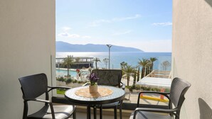 Ein Balkon mit rundem Tisch, zwei Stühlen und Blick auf Meer und Berge.