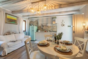 A modern kitchen with a stone backsplash, a dining table set for two, and a white sofa in the living area. - Dimora Della Rocca Private Garden, WIFI, BBQ & Parking, Angera, Italy (Angera)